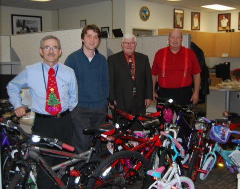 Men stand behind bicycles collected for Toys for Tots.