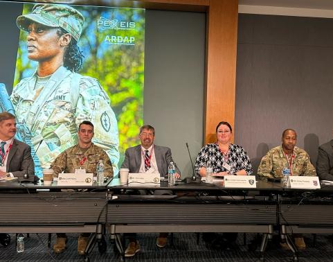 Six Army panelists sit on the dais at the ATIS Industry Day