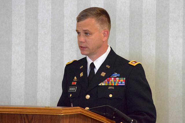 Soldier in dress uniform speaks behind podium.