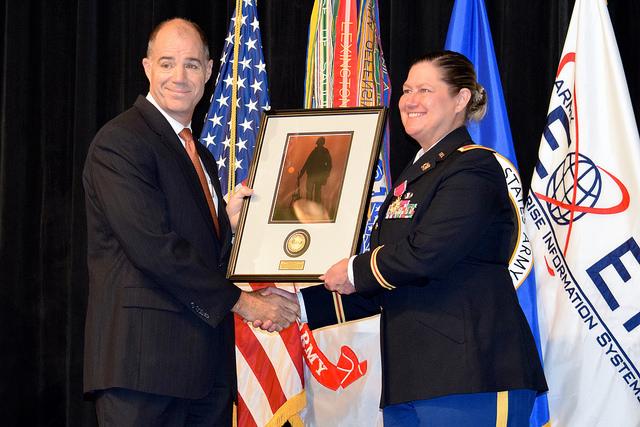 Two people hold framed image.