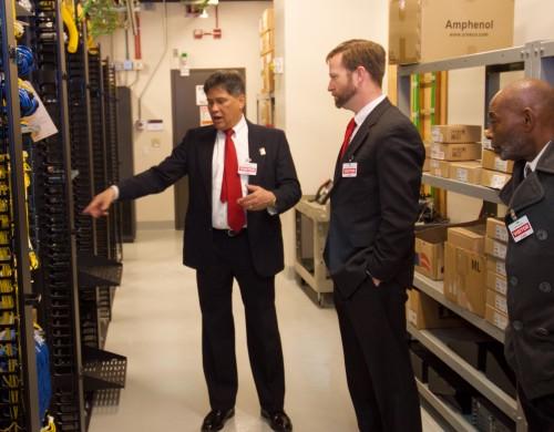 Man points to machine while talking to another man.